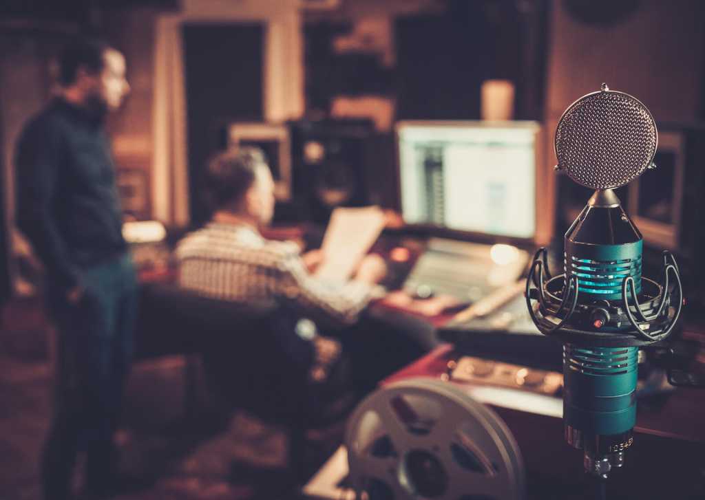 Sound engineer and producer working together at mixing panel in the boutique recording studio.