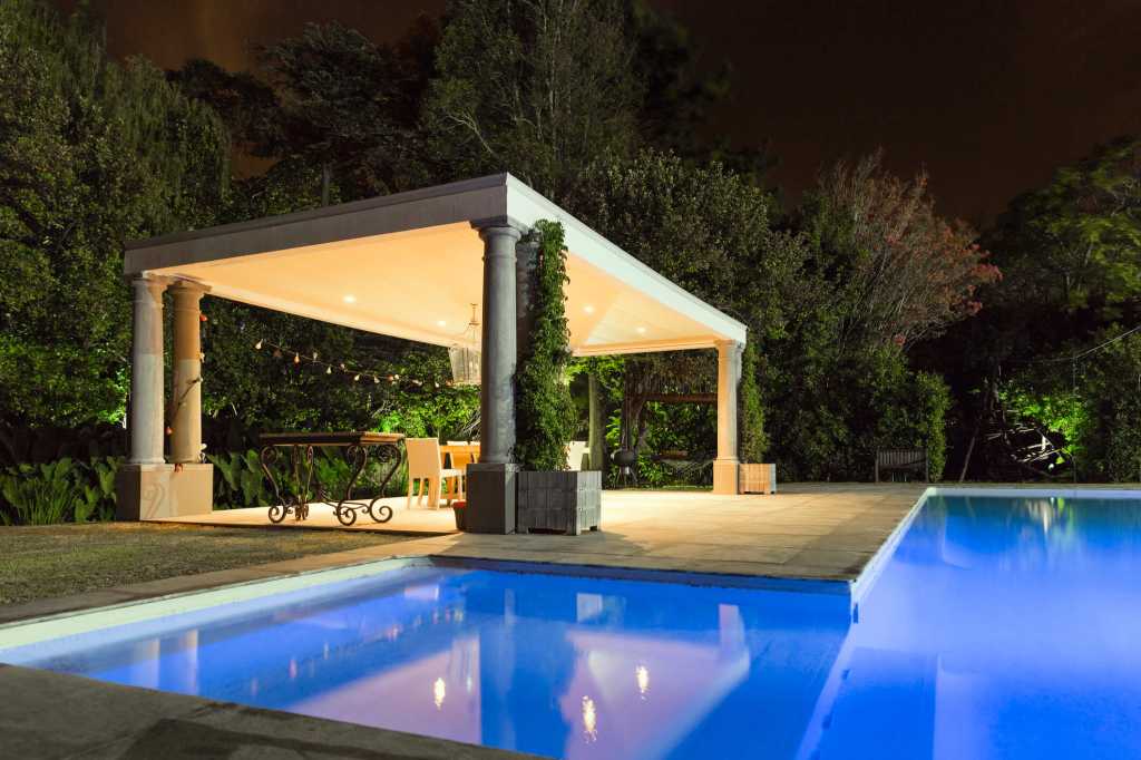 Illuminated gazebo at poolside during night
