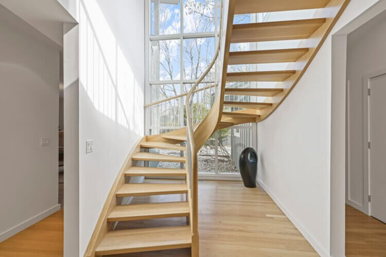 Beautiful curvy wooden staircase connects the separate parts of the home; Sag Harbor Village; Art gallery; modern; minimalist summer home